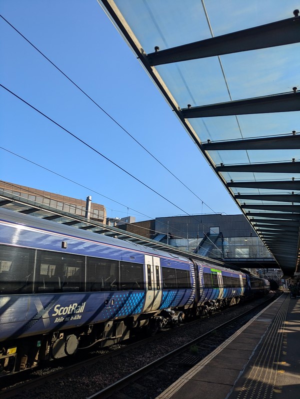 Image of the train platform, a blue Scotrail train is on the tracks.