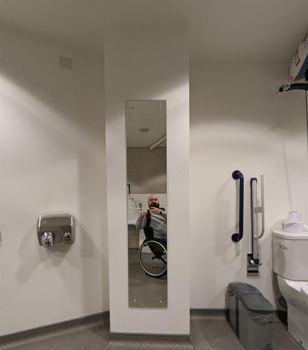 Image of a person in a wheelchair taking a picture of themselves in a mirror