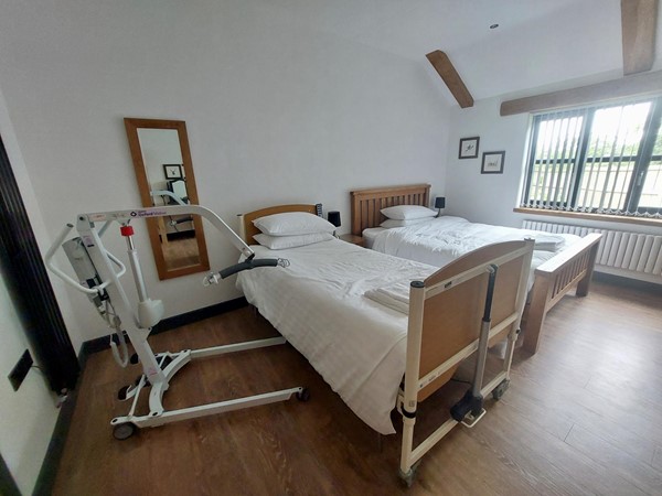 View of one of the main bedrooms, showing a profiling bed and hoist