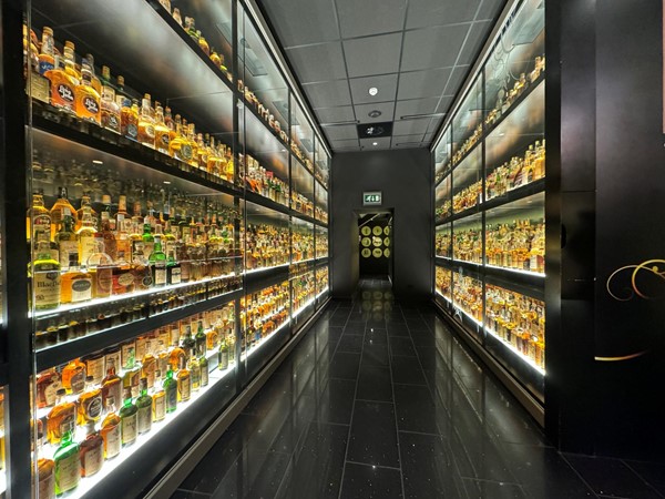 The whisky collection with floor to ceiling bottles of whisky on their glass shelves.