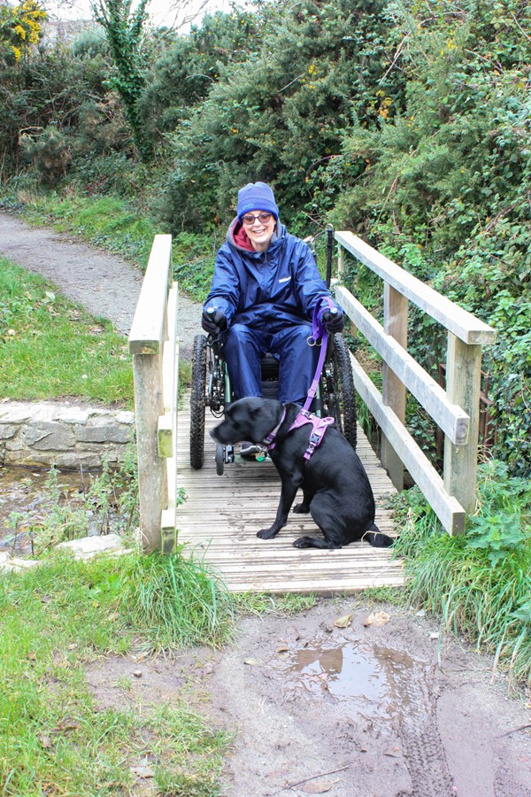 Me in my trike with dog on a small wooden footbridge.