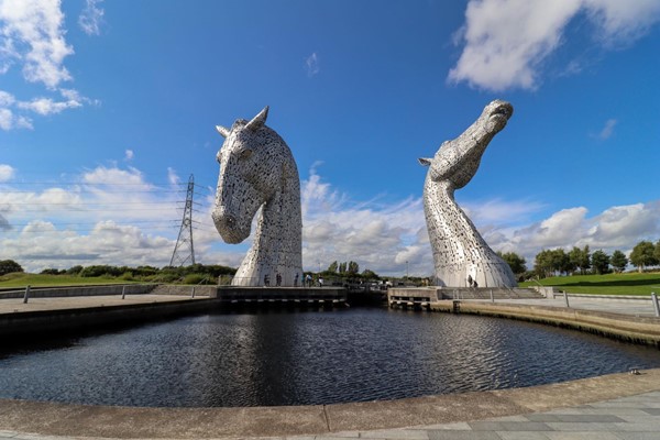 Kelpies with lake in front and paths going around in both directions.