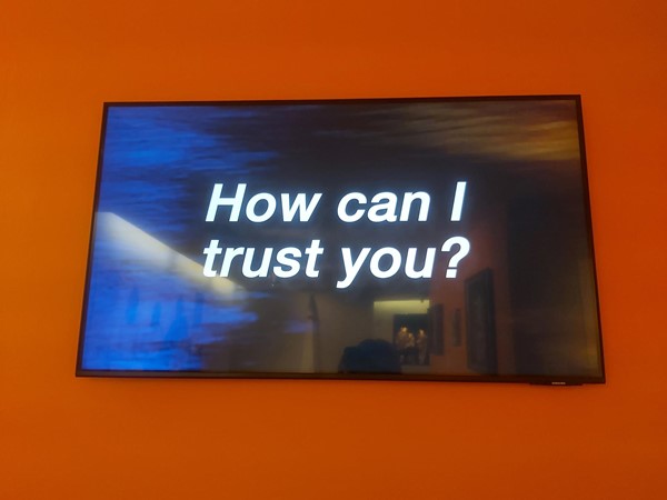 The words "How can I trust you?" on a television