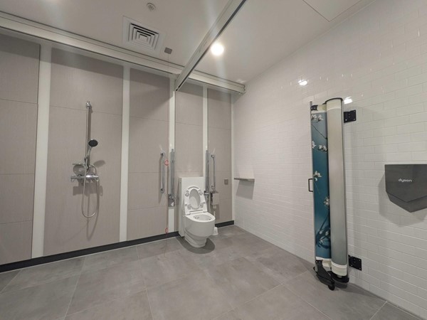 Image of the toilet, showing the toilet, grabrails, privacy screen and hand dryer