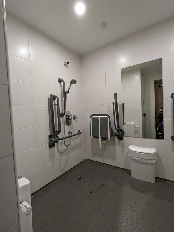 Image of the shower, shower seat and mirror in one of the disabled toilets,