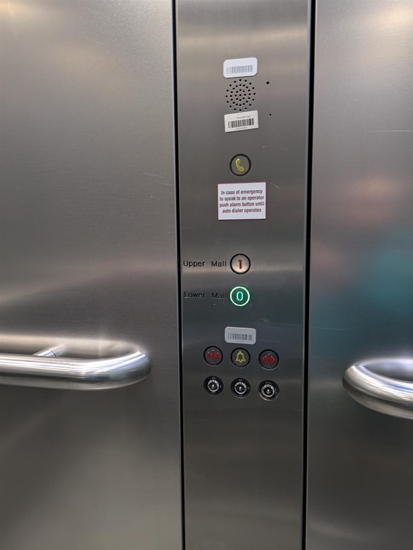 Image of grabrail in lift. The lift buttons do not have Braille markings