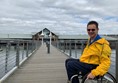 Paul wheeling across the walkway over the water of the harbour basin.