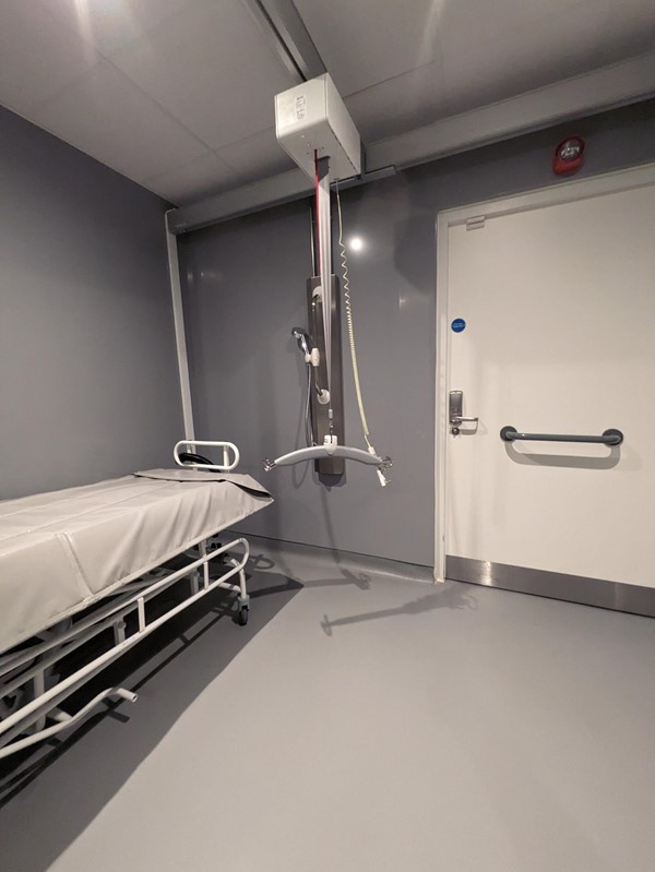 Image of the changing places toilet, showing the change bed, ceiling track hoist and shower