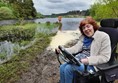 Image of a wheelchair user sitting beside a lake