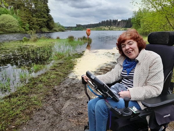 Image of a wheelchair user sitting beside a lake