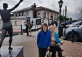 LondonMarmot on small scooter on the promenade next to the sea in Cobh. The Titanic Experience is in the old White Star Line building in the background. The statue on the left is of Irish athletics champion Sonia O'Sullivan