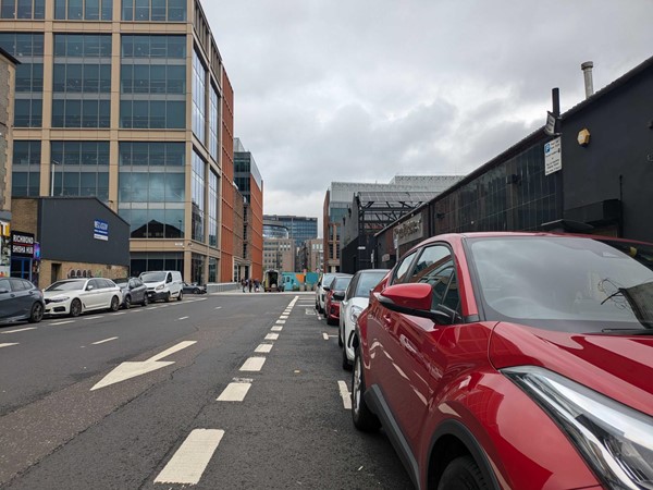 Image of the Tradeston Street parking spaces, a close-up of a red car with others parked behind.