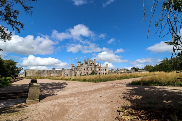 Distant view of castle with a short flight of steps to one side but a wide path alternative.