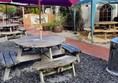 Picture of outdoor seating. A wooden round table with benches and an umbrella