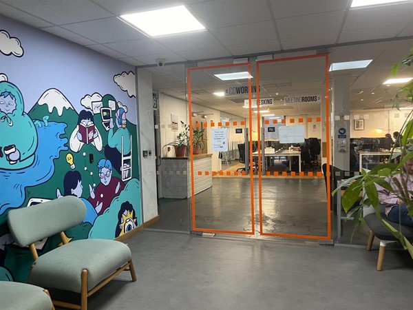 Double glass doors that are openable by a fob on the painted wall. There is a low chair against the wall before the double doors.