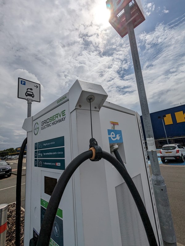 Image of a white electric car charging at a car park emitting zero emissions and promoting sustainable transportation.