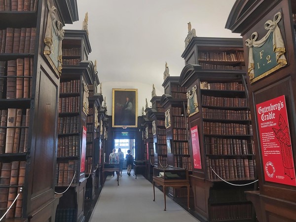 Image of a room with bookshelves and people walking