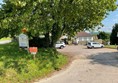 Image of a oad with a sign and cars parked on the side