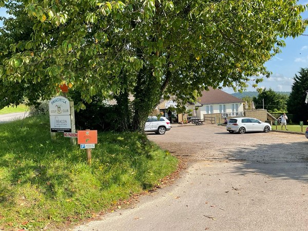 Image of a oad with a sign and cars parked on the side