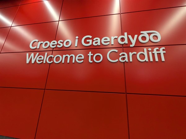 Image of a red wall with white writing reading "Welcome to Cardiff" in English and Welsh