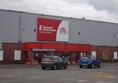 This photo shows the Car park and main doors in to the store. There is one Blue Badge space on the Left hand side of the door. however it is very close to the wall.