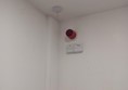 Image of a white wall with a red alarm on it