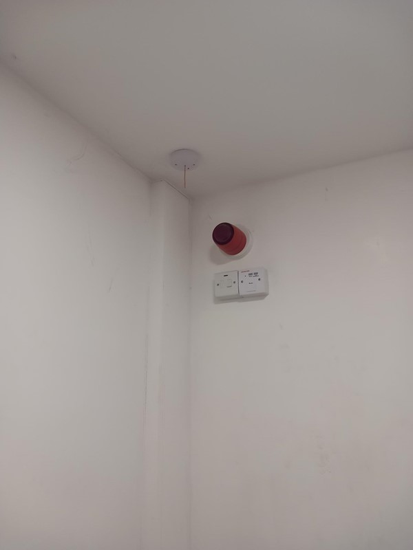 Image of a white wall with a red alarm on it