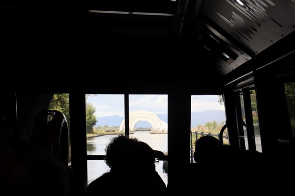 Boat leaving dark tunnel and moving towards the wheel in the distance.