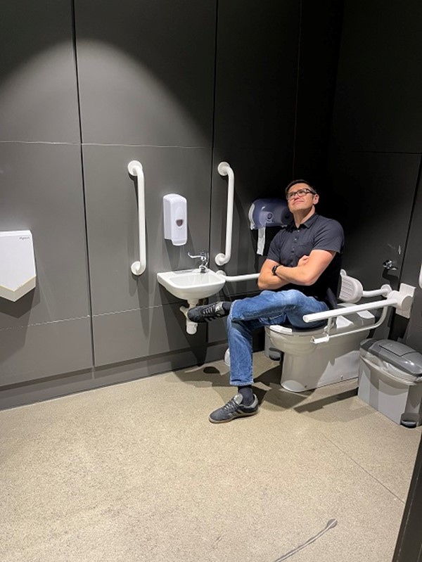 Image of a man sitting on an accessible toilet