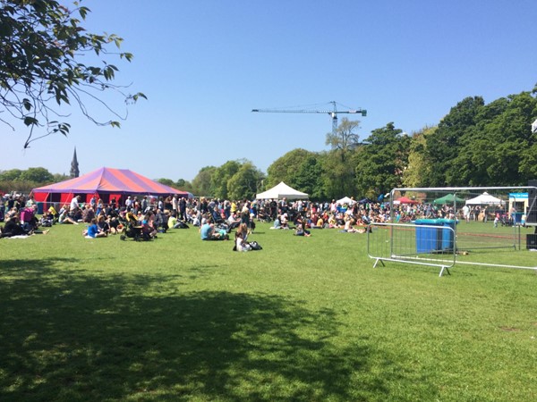 Photo of people sitting in front of the main stage on  the grass.