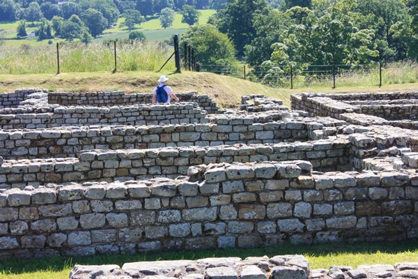 Ruins in the foreground with grass bank showing that the fence is raised above the ruins.