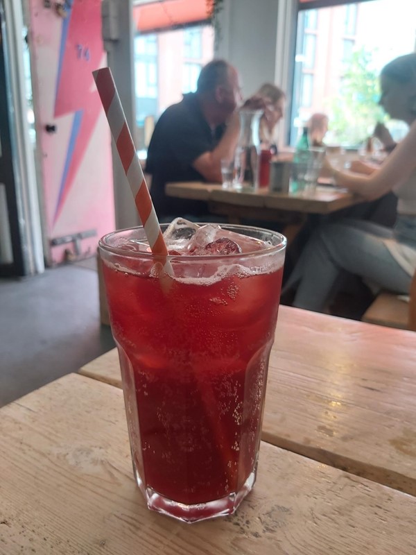 Image of a glass with a straw and a red drink on a table