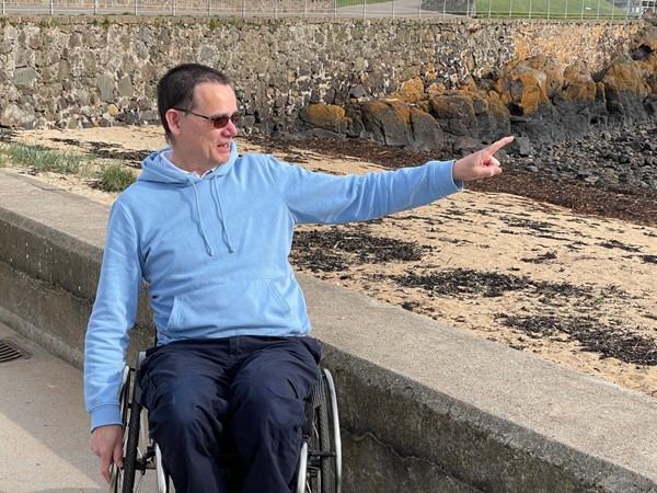 Paul pointing out something in the distance as he sits by the seashore