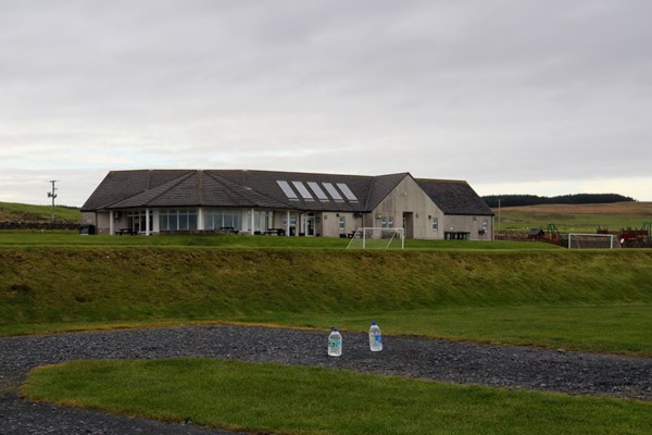 Picture of  a concrete building a football pitch and two bottles of water