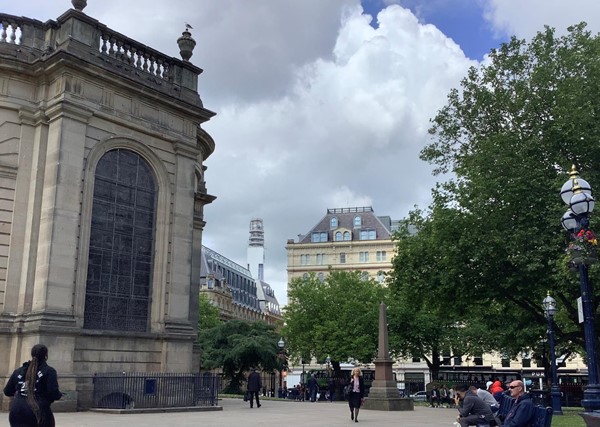 Public area with an older looking building and trees beside it.