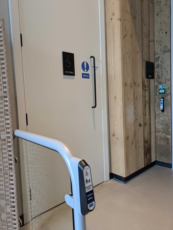 Image of a handrail with a touchpad in front of a white door