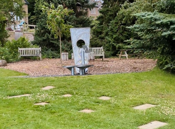 Image of a park with benches and a sculpture