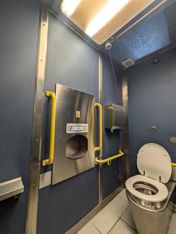 image of the accessible toilet at Mount Florida Railway Station.  The red cord is tied behind a paper towel dispenser.