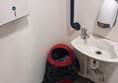 Image of a red bin can next to a sink with grabrails