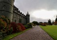 Gravel path going along the back wall of the castle with lawns to the right.