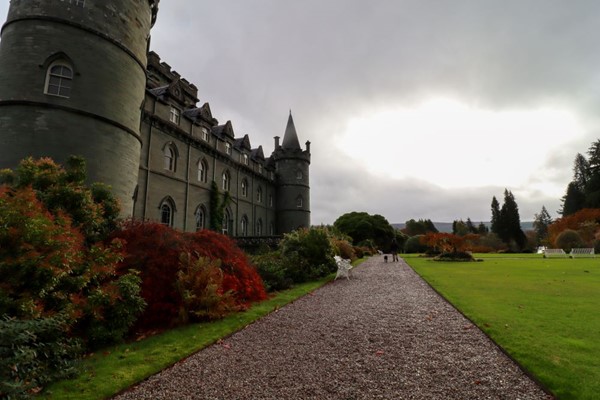 Gravel path going along the back wall of the castle with lawns to the right.