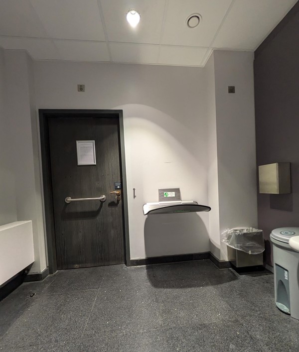 Image of the interior of the toilet, to the right of the door is a changing table suitable for babies and toddlers.