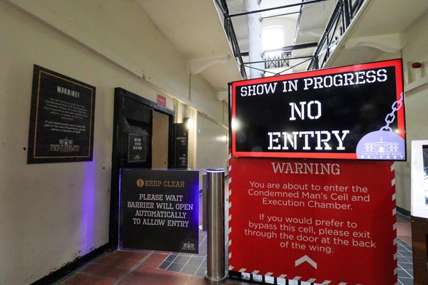 Walkway with a closed gate and a large sign saying Show in progress, no entry.