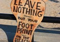 Footprint sign saying, leave nothing but your footprint on the beach.