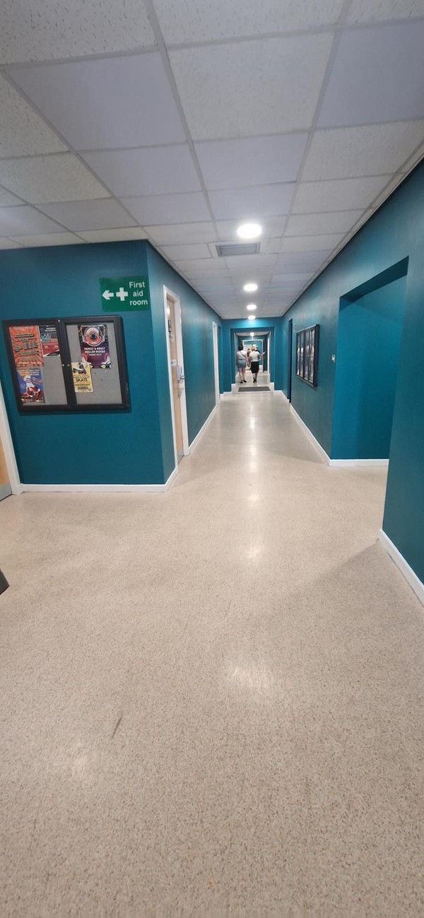 Image of a hallway with blue walls and a white floor.