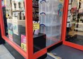 The entrance to the shop with a sign showing a wheelchair symbol and the words 'For assistance please ring the bell'. The doorbell button unit is missing.