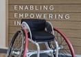 Image of a wheelchair with a sign in the background