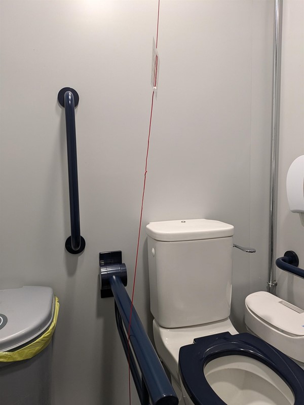 Image of red cord tied around grab rails in the accessible toilet