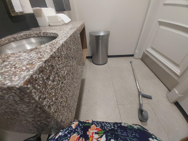 A bathroom sink with a walking aid and a trash can