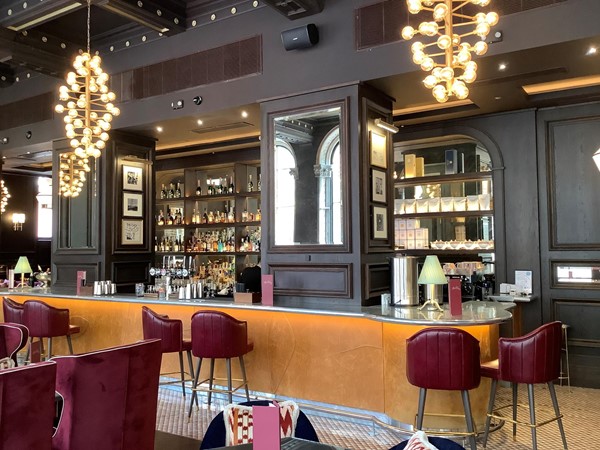 Interior shot of a bar with bar stools and grey walls with dangling lights